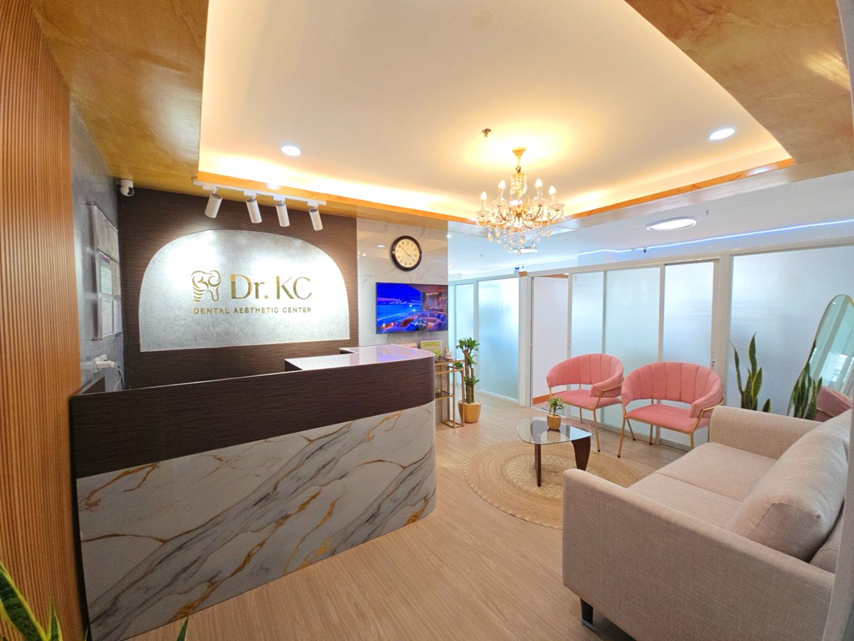 Reception desk and waiting area of Dr. KC Dental Aesthetic Center, with pink armchairs and a cream sofa